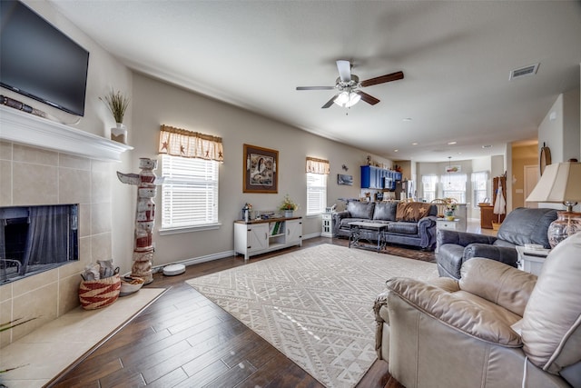 living room featuring hardwood / wood-style flooring, a tile fireplace, and ceiling fan