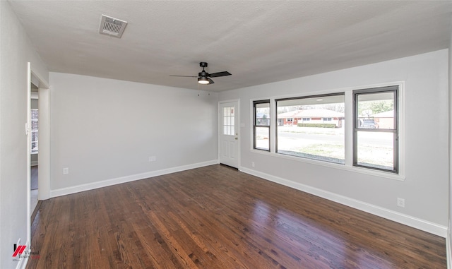 empty room featuring ceiling fan, dark wood-type flooring, and a textured ceiling