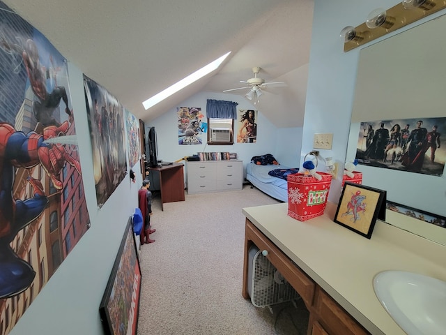 interior space featuring ceiling fan, vaulted ceiling with skylight, light carpet, and sink