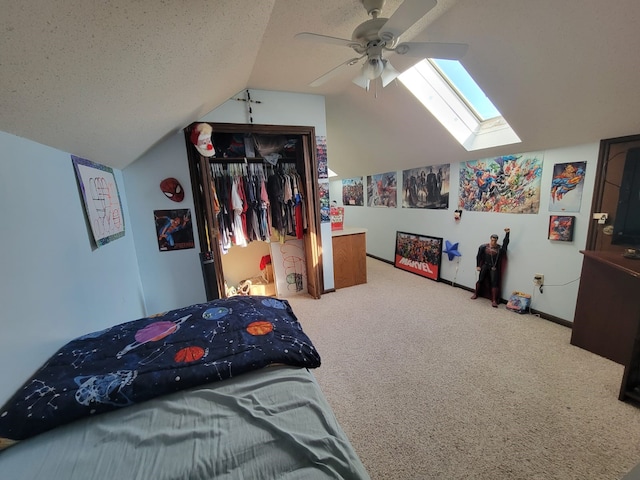 carpeted bedroom featuring a closet, ceiling fan, vaulted ceiling with skylight, and a textured ceiling