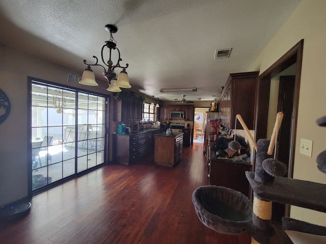 interior space with a textured ceiling, dark hardwood / wood-style floors, and a notable chandelier