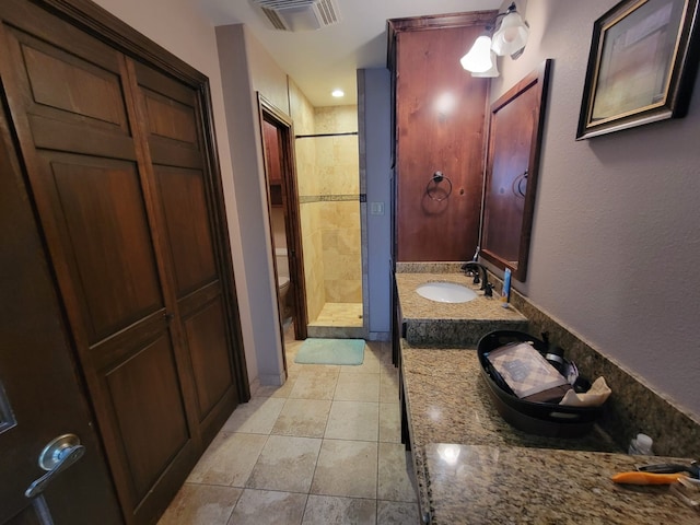 bathroom featuring tile patterned flooring, vanity, tiled shower, and toilet