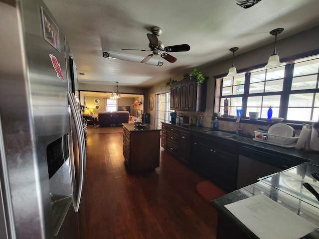 kitchen with sink, a center island, dark brown cabinets, dark hardwood / wood-style floors, and stainless steel fridge