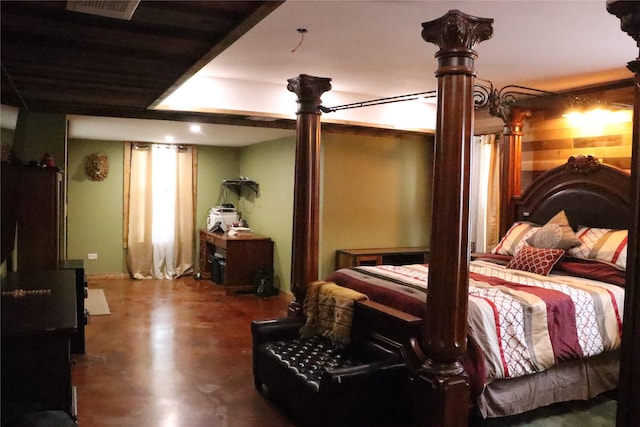 bedroom with ornate columns and concrete floors