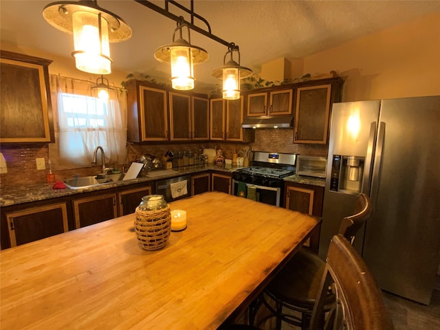 kitchen with sink, a textured ceiling, appliances with stainless steel finishes, pendant lighting, and backsplash