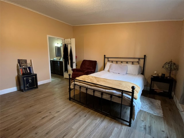 bedroom featuring connected bathroom, ornamental molding, hardwood / wood-style floors, and a textured ceiling