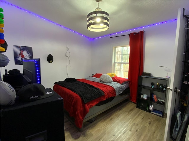 bedroom with hardwood / wood-style floors and a notable chandelier