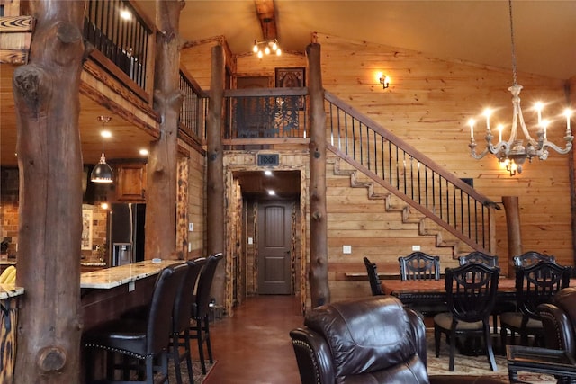 dining room featuring an inviting chandelier, high vaulted ceiling, and wood walls