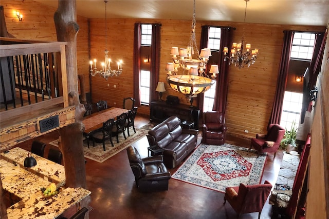 living room featuring a notable chandelier, wooden walls, and concrete floors