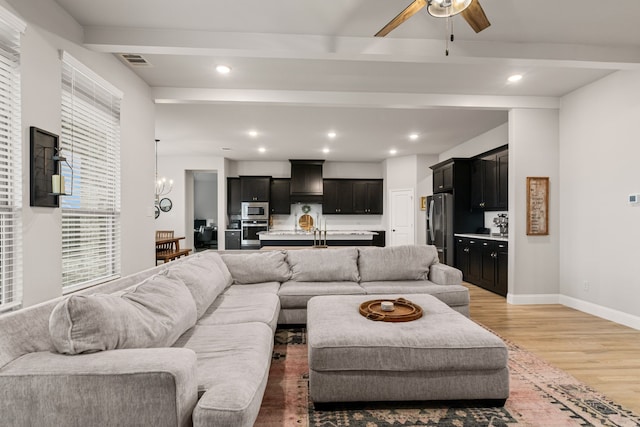 living area featuring light wood-type flooring, baseboards, beamed ceiling, and recessed lighting