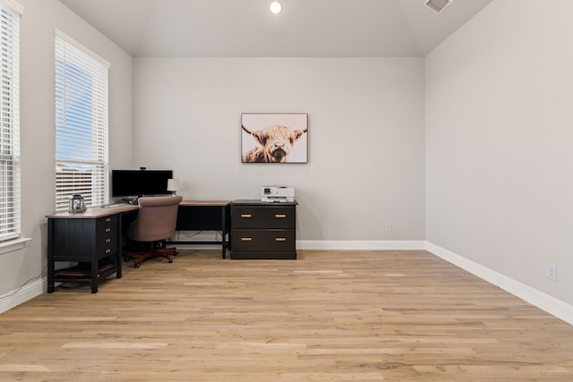 office space featuring vaulted ceiling, light wood-type flooring, visible vents, and baseboards