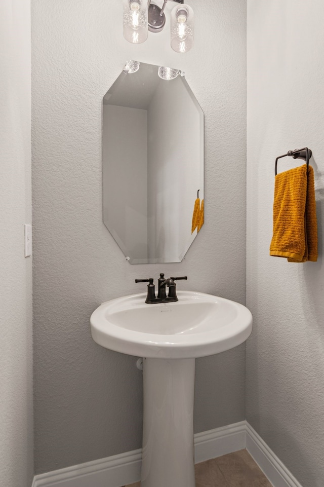 bathroom with tile patterned flooring, a sink, and baseboards