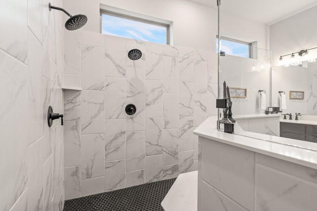 bathroom with a tile shower and vanity