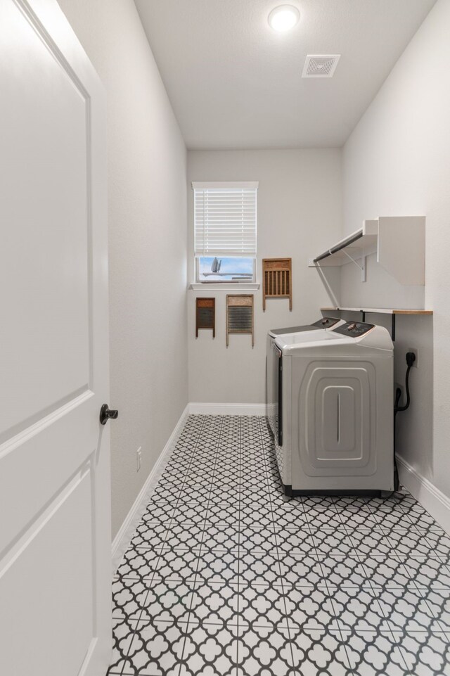 washroom featuring laundry area, baseboards, visible vents, tile patterned floors, and washer and dryer