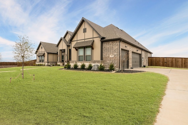 tudor house featuring a shingled roof, concrete driveway, fence, a front lawn, and brick siding