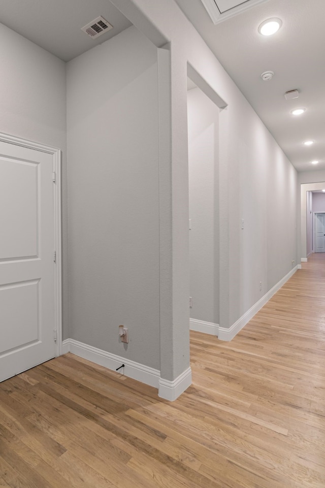 hallway with light wood-type flooring, baseboards, visible vents, and recessed lighting