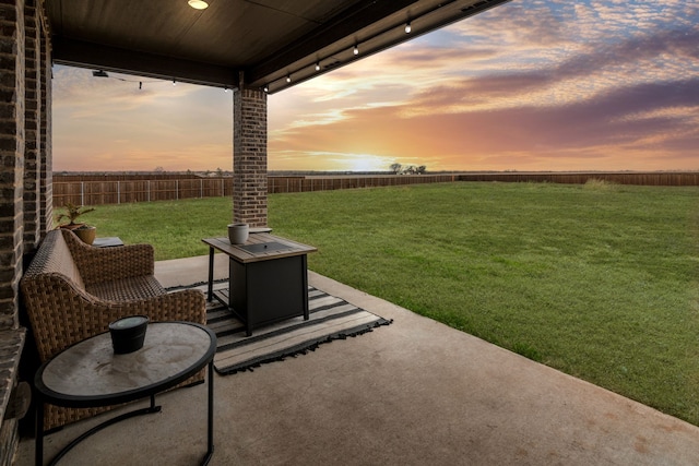 patio terrace at dusk featuring a lawn and an outdoor fire pit