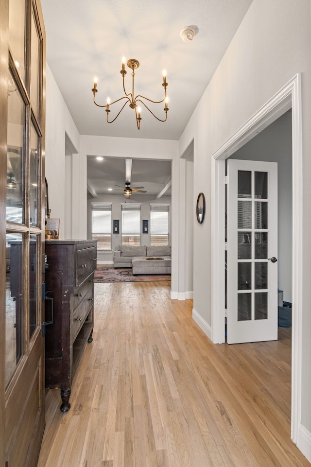 corridor with an inviting chandelier and light hardwood / wood-style flooring