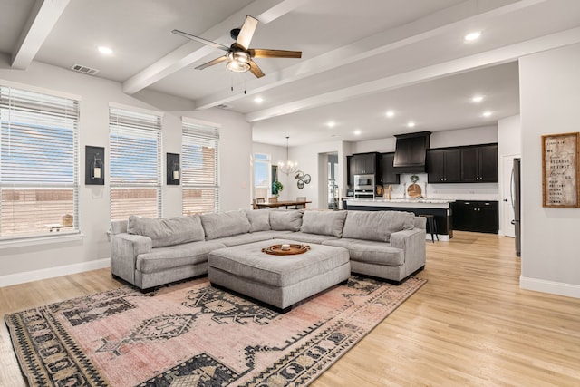 living room with beamed ceiling, ceiling fan with notable chandelier, and light hardwood / wood-style floors