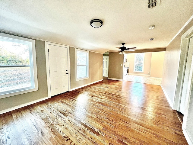 foyer entrance featuring ceiling fan, light hardwood / wood-style flooring, and a textured ceiling