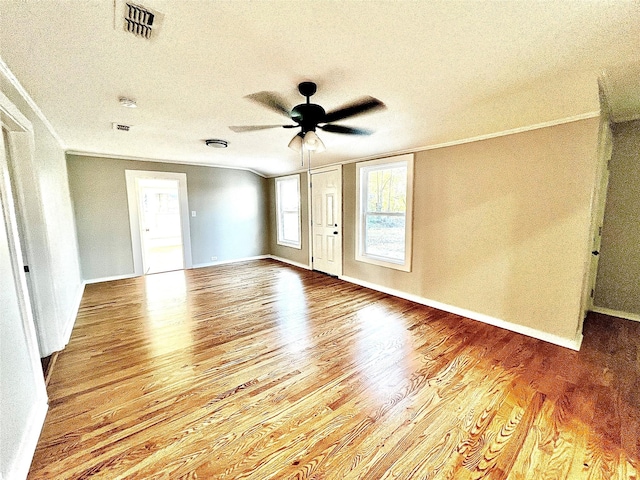 empty room featuring hardwood / wood-style flooring, ornamental molding, a textured ceiling, and ceiling fan