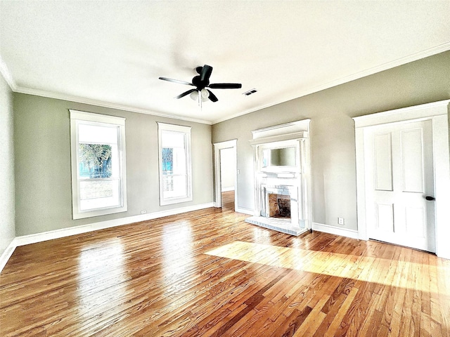 unfurnished living room featuring light hardwood / wood-style flooring, crown molding, a fireplace, and ceiling fan