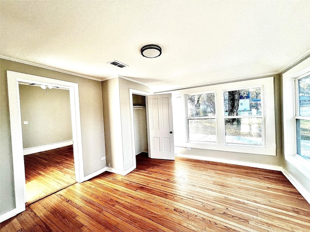 unfurnished bedroom featuring light wood-type flooring, crown molding, and multiple windows