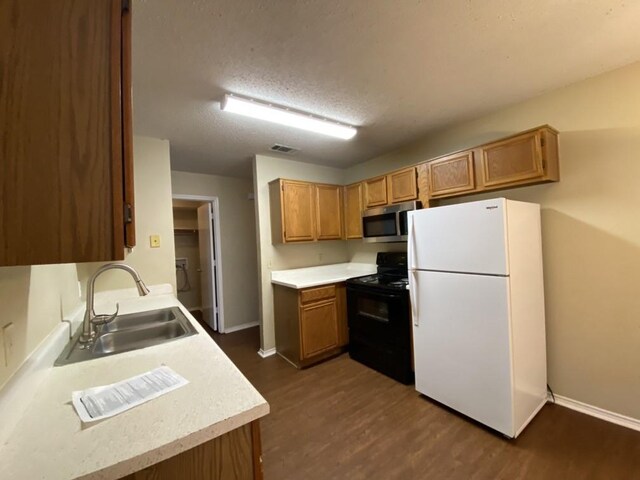 kitchen with black electric range oven, sink, white fridge, dark wood-type flooring, and a textured ceiling