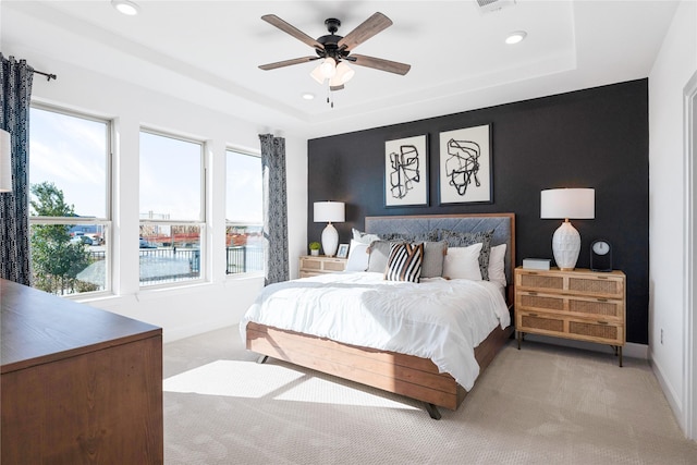 carpeted bedroom featuring a raised ceiling and ceiling fan