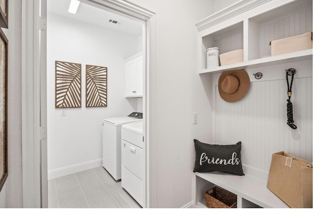 clothes washing area with cabinets, light tile patterned floors, and independent washer and dryer