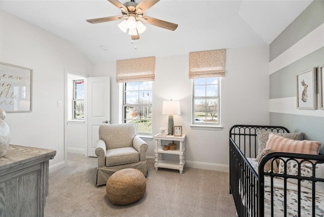 bedroom featuring ceiling fan, a nursery area, vaulted ceiling, and light carpet