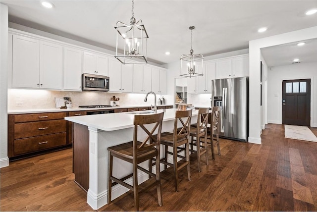 kitchen featuring a kitchen breakfast bar, appliances with stainless steel finishes, sink, white cabinets, and a center island with sink