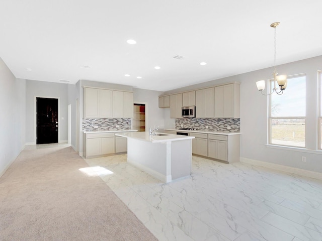 kitchen with pendant lighting, sink, a kitchen island with sink, and tasteful backsplash