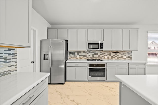 6225 Kent Ln, Celina, TX 76227 - kitchen featuring appliances with stainless steel finishes, light marble finish flooring, light countertops, backsplash, and gray cabinetry