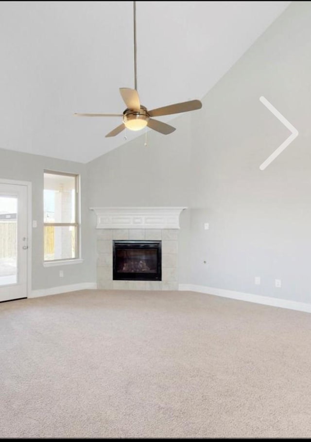 unfurnished living room with a tile fireplace, carpet, ceiling fan, and lofted ceiling