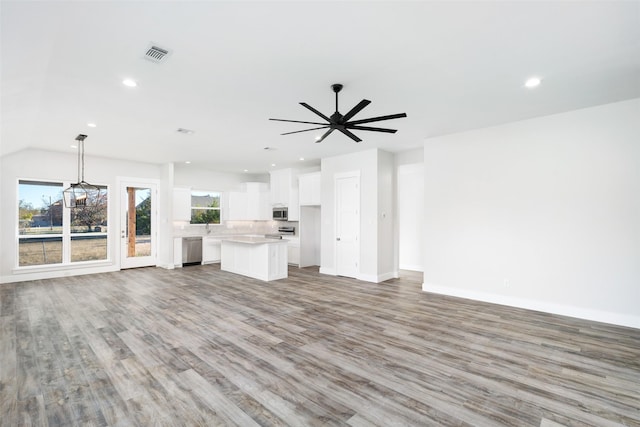 unfurnished living room featuring ceiling fan, lofted ceiling, sink, and light wood-type flooring