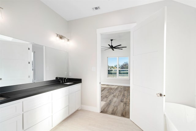 bathroom featuring hardwood / wood-style flooring, ceiling fan, vanity, and a washtub