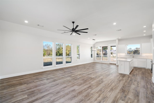 unfurnished living room with light wood-type flooring, ceiling fan, and sink