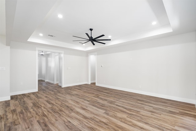 spare room featuring ceiling fan, wood-type flooring, and a raised ceiling