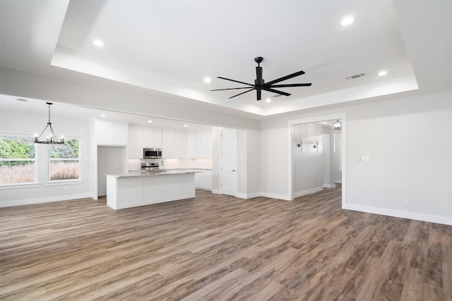 unfurnished living room with a tray ceiling and light hardwood / wood-style floors