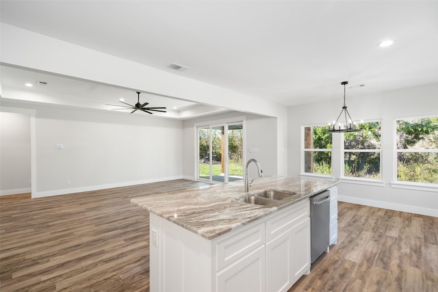 kitchen with sink, light stone counters, an island with sink, white cabinets, and stainless steel dishwasher