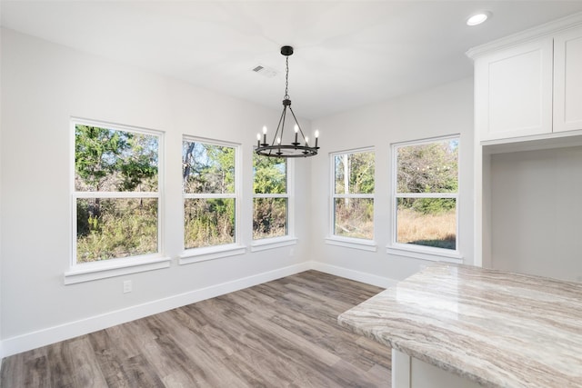 unfurnished dining area featuring hardwood / wood-style flooring and a chandelier