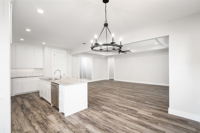 kitchen featuring dishwasher, light stone counters, white cabinets, a center island with sink, and decorative light fixtures