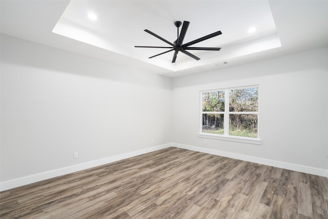 spare room with hardwood / wood-style flooring, ceiling fan, and a tray ceiling