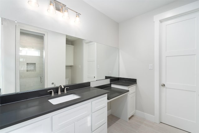 bathroom featuring vanity, toilet, a shower with shower door, and wood-type flooring