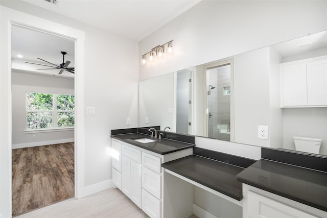 bathroom featuring hardwood / wood-style flooring, vanity, walk in shower, ceiling fan, and toilet