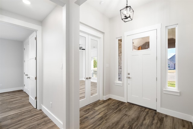 foyer featuring dark hardwood / wood-style floors, a notable chandelier, and french doors