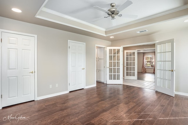 empty room featuring a tray ceiling, ceiling fan, french doors, and crown molding