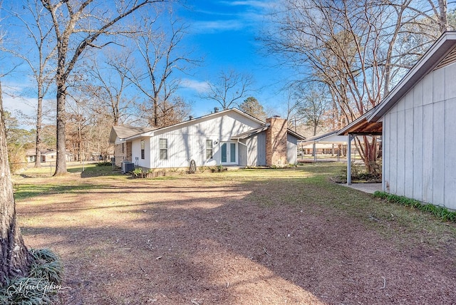 exterior space featuring a yard, a carport, and central air condition unit