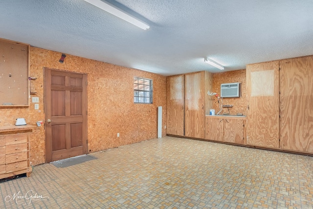 basement with wood walls, a textured ceiling, and a wall mounted AC